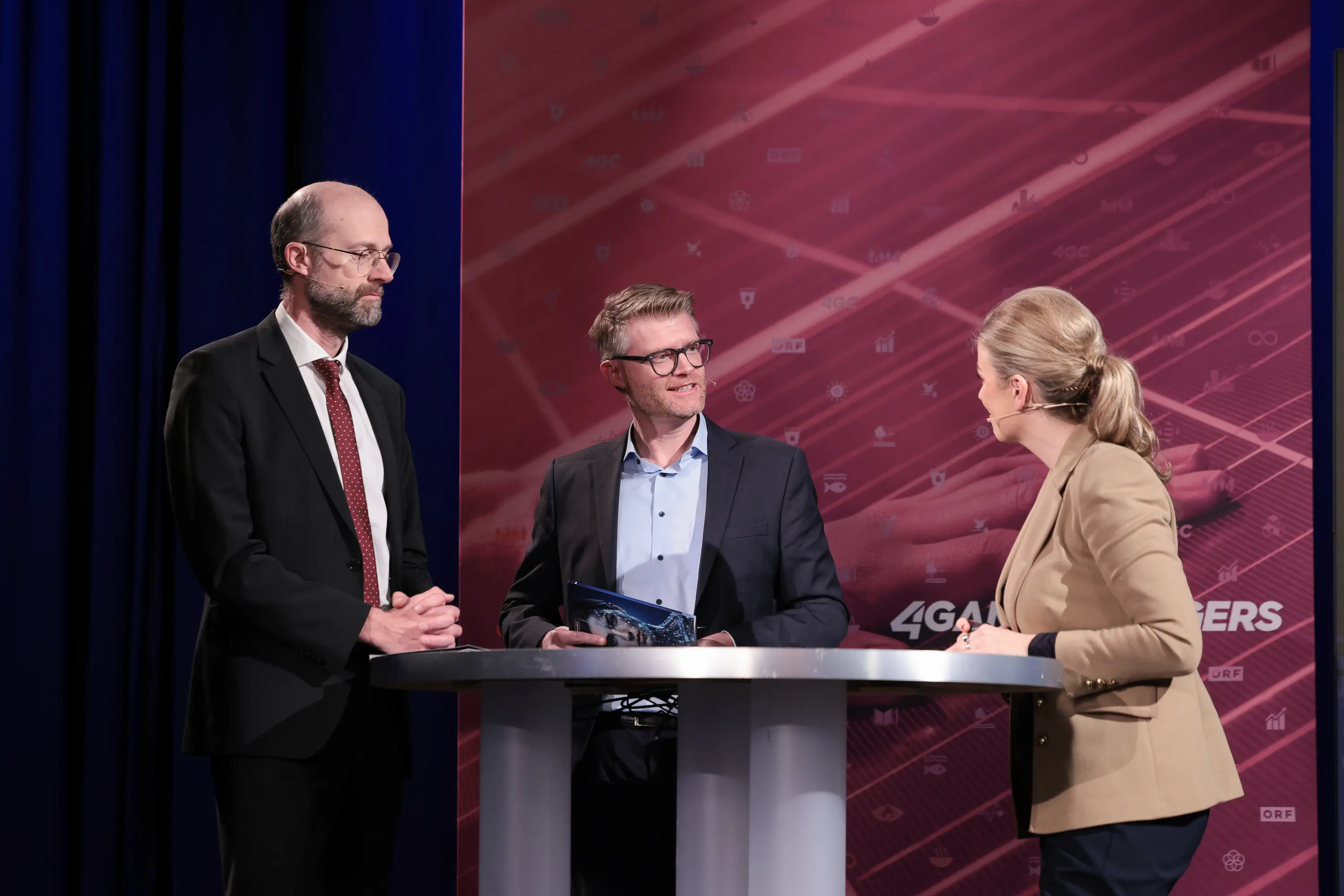 Impressionen von der Jahrbuch-Präsentation im PULS 24 Studio am 13. Jänner 2026. Die Bildergalerie zeigt verschiedene Momente der Veranstaltung mit Redner:innen am Podium, Gästen im Publikum und Teilnehmer:innen im Gespräch.